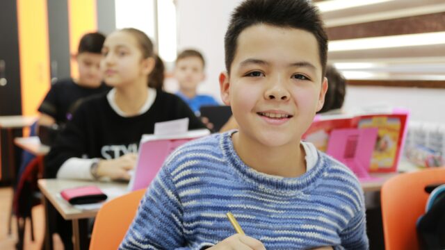 boy in blue and white striped long sleeve shirt holding pencil